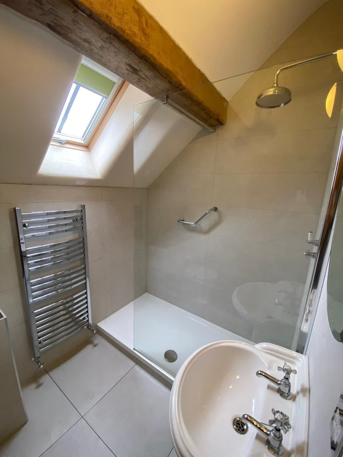 A loft shower room with a skylight, a towel radiator and a basin