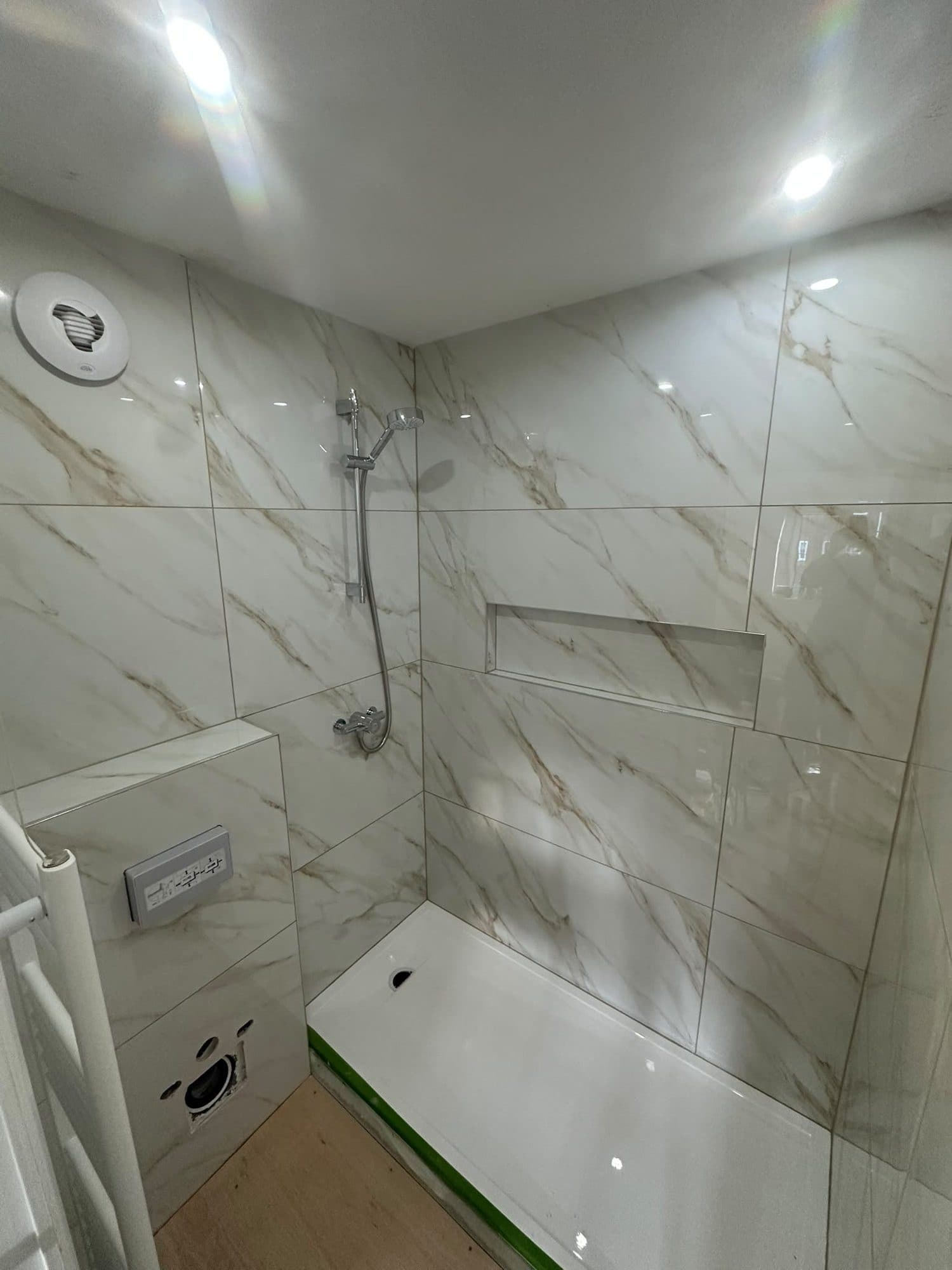 A marble-effect tiled shower with a recessed niche