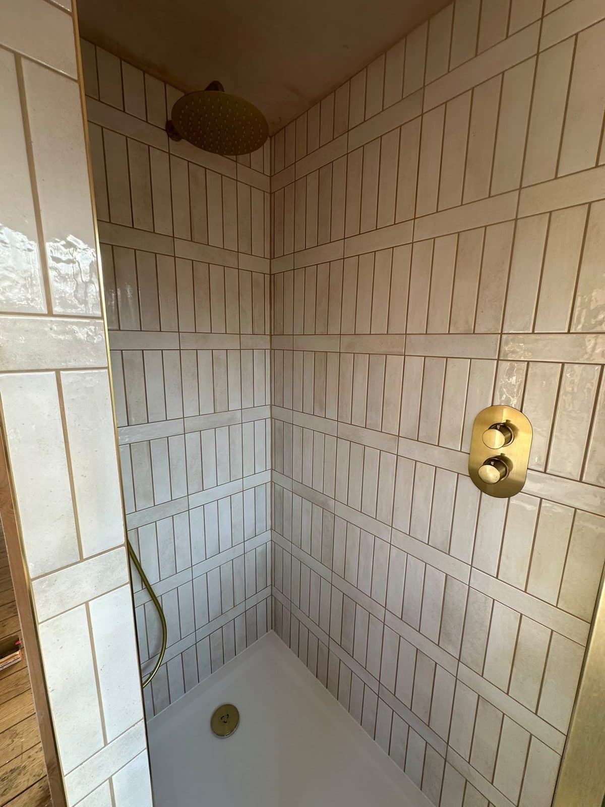 Vertical cream tiles in a shower with gold fittings
