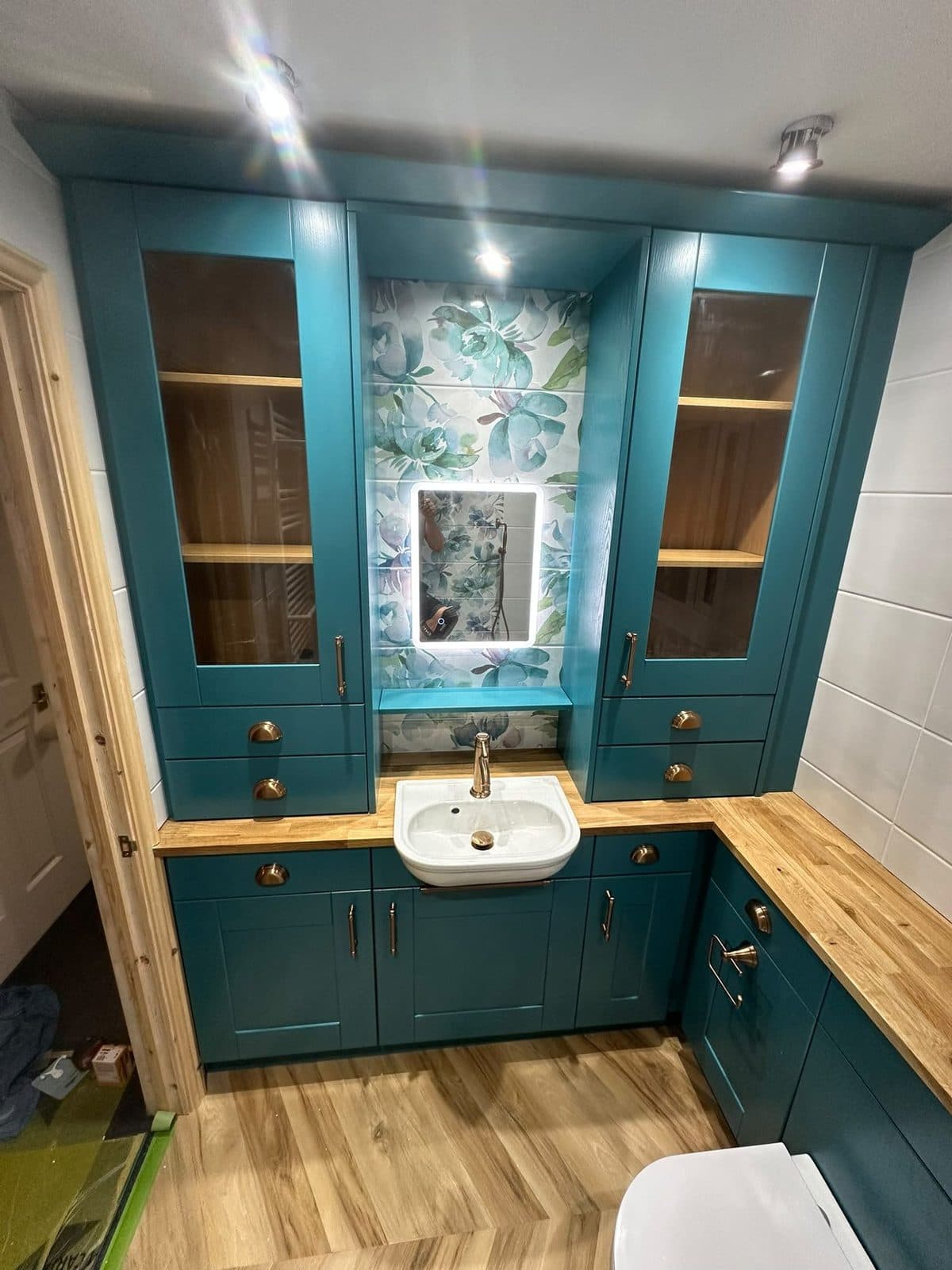 Teal fitted bathroom units with an oak worktop